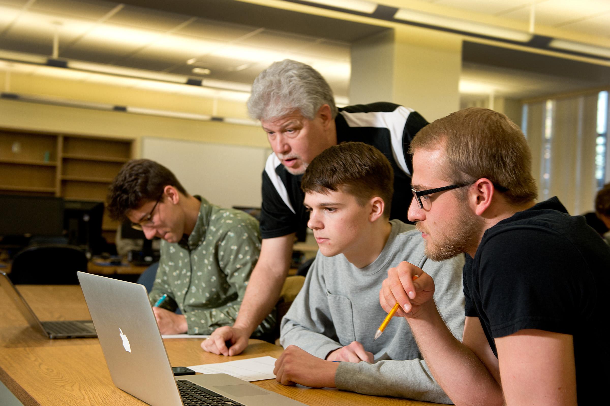 Professor and students working on computers 
